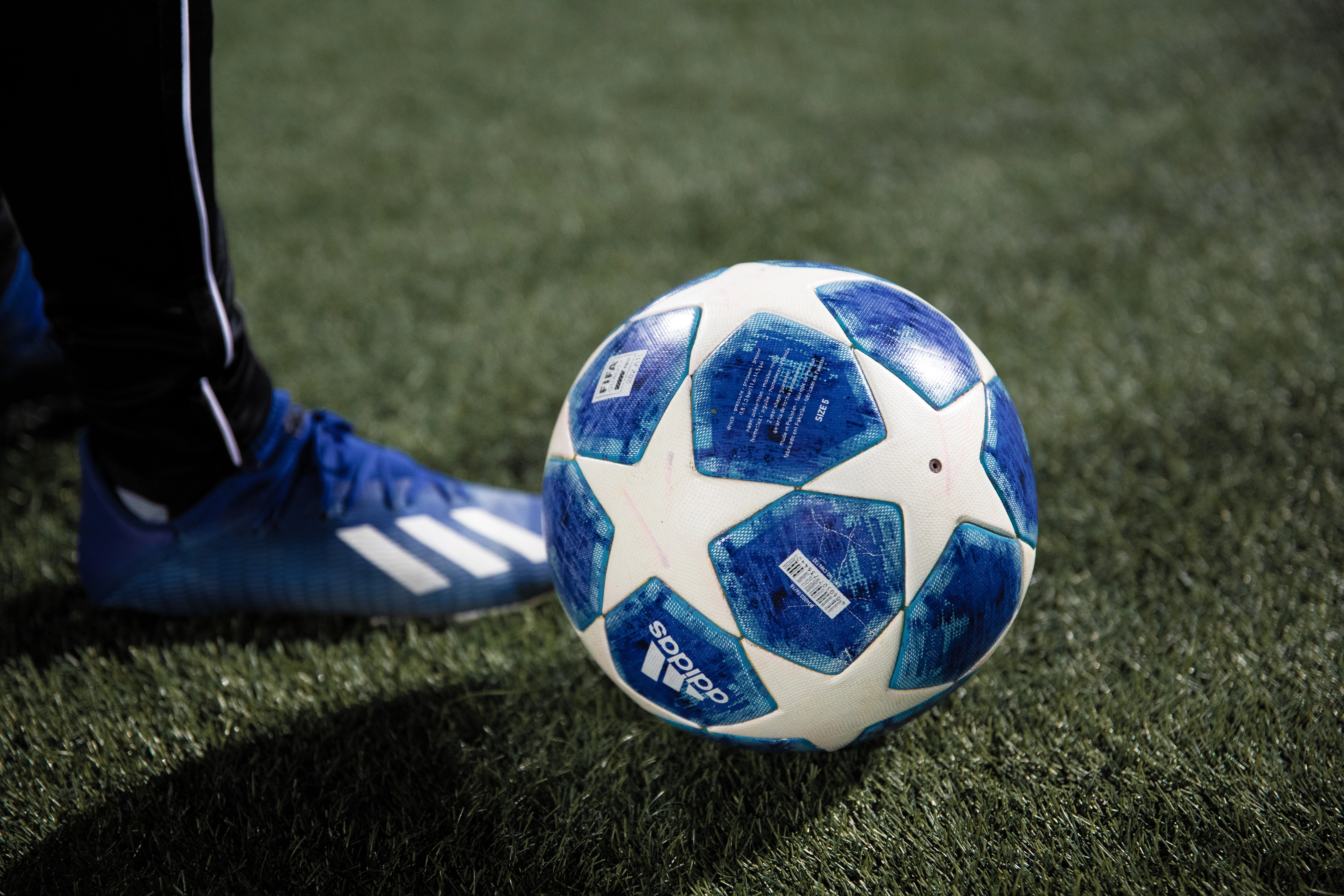 Футбольный мяч и нога футболиста на фоне футбольного поля