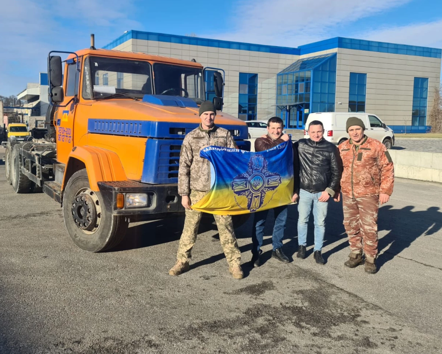 Віталій та Владислав Гришки з військовослужбовцями ЗСУ на фоні переданої техніки.webp