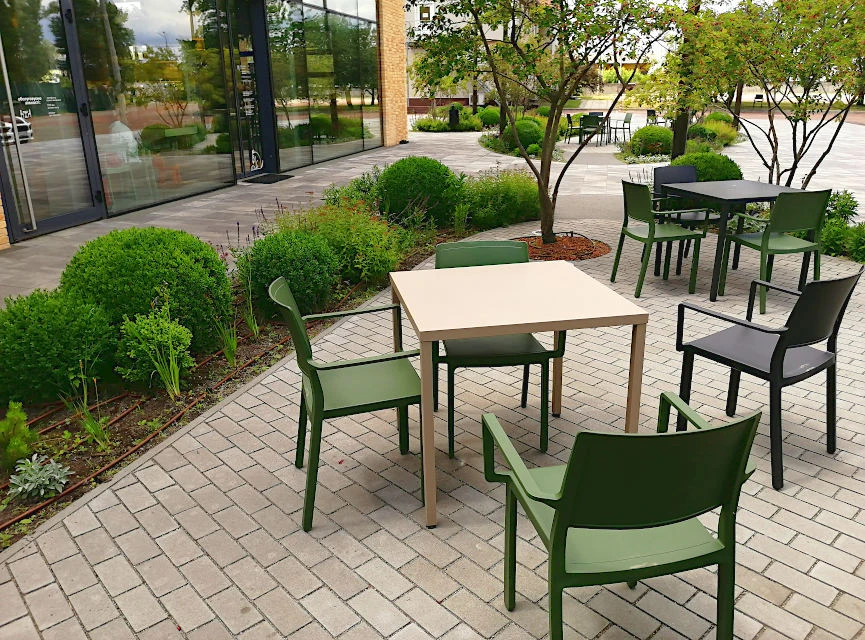 Металеві обідні столи просто неба на майданчику біля ресторану.