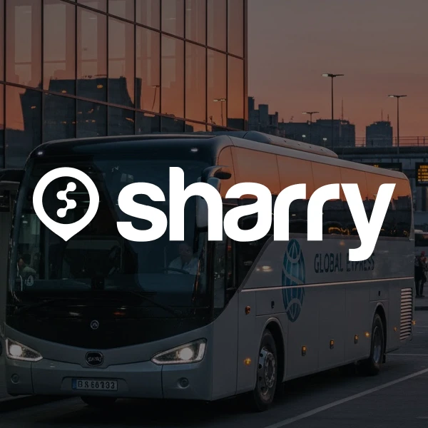 logo i nazwa firmy Sharry na tle srebrnego autokaru turystycznego zaparkowanego przed szklanym budynkiem o zmierzchu