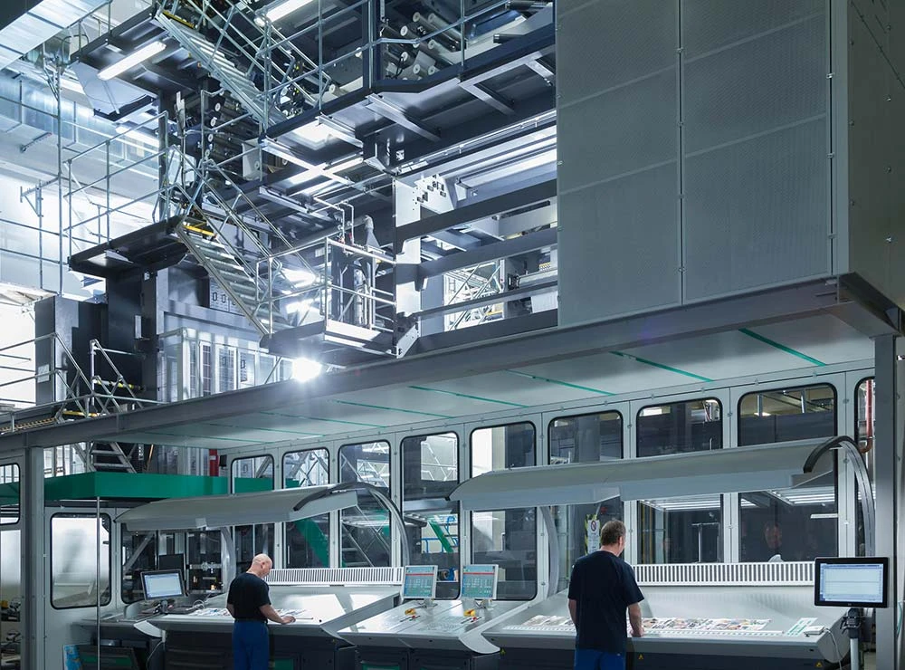 Operators monitoring automated industrial web offset printing systems