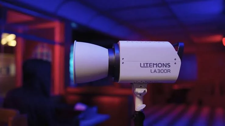 Білий моноблок Godox Litemons LA300R зі стандартним рефлектором у затемненій кімнаті з синім фоновим підсвічуванням.
