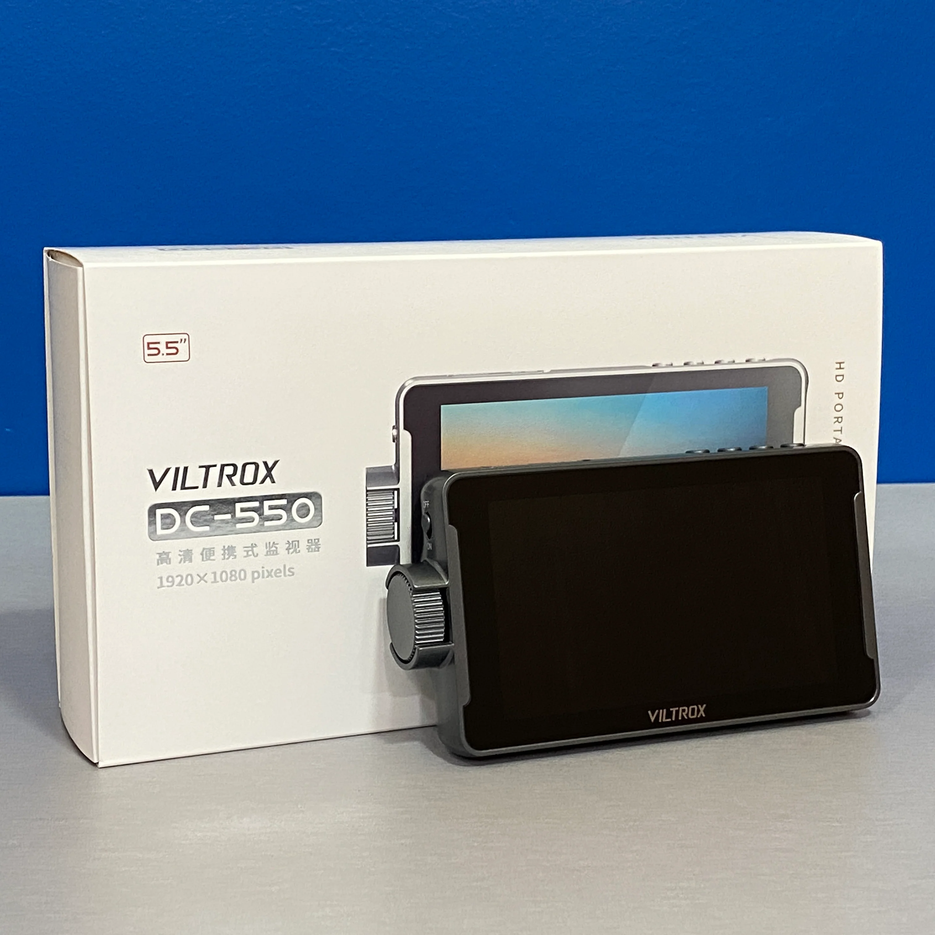 Монітор Viltrox DC-550 у фірмовій коробці поруч із бічним регулювальним колесом
