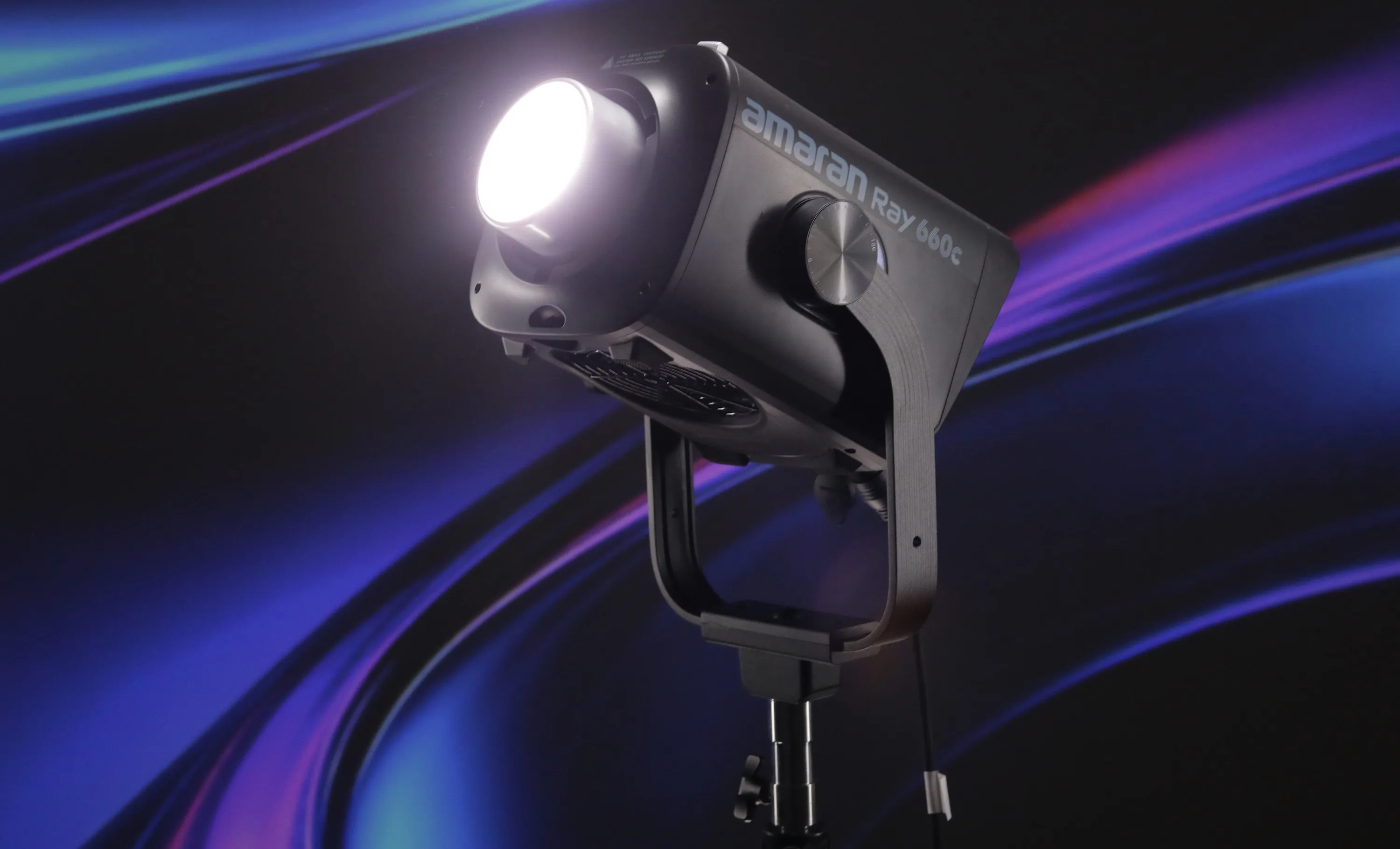 Моноблок Amaran Ray 660c на масивній металевій лірі в увімкненому стані випромінює яскравий білий промінь у студії