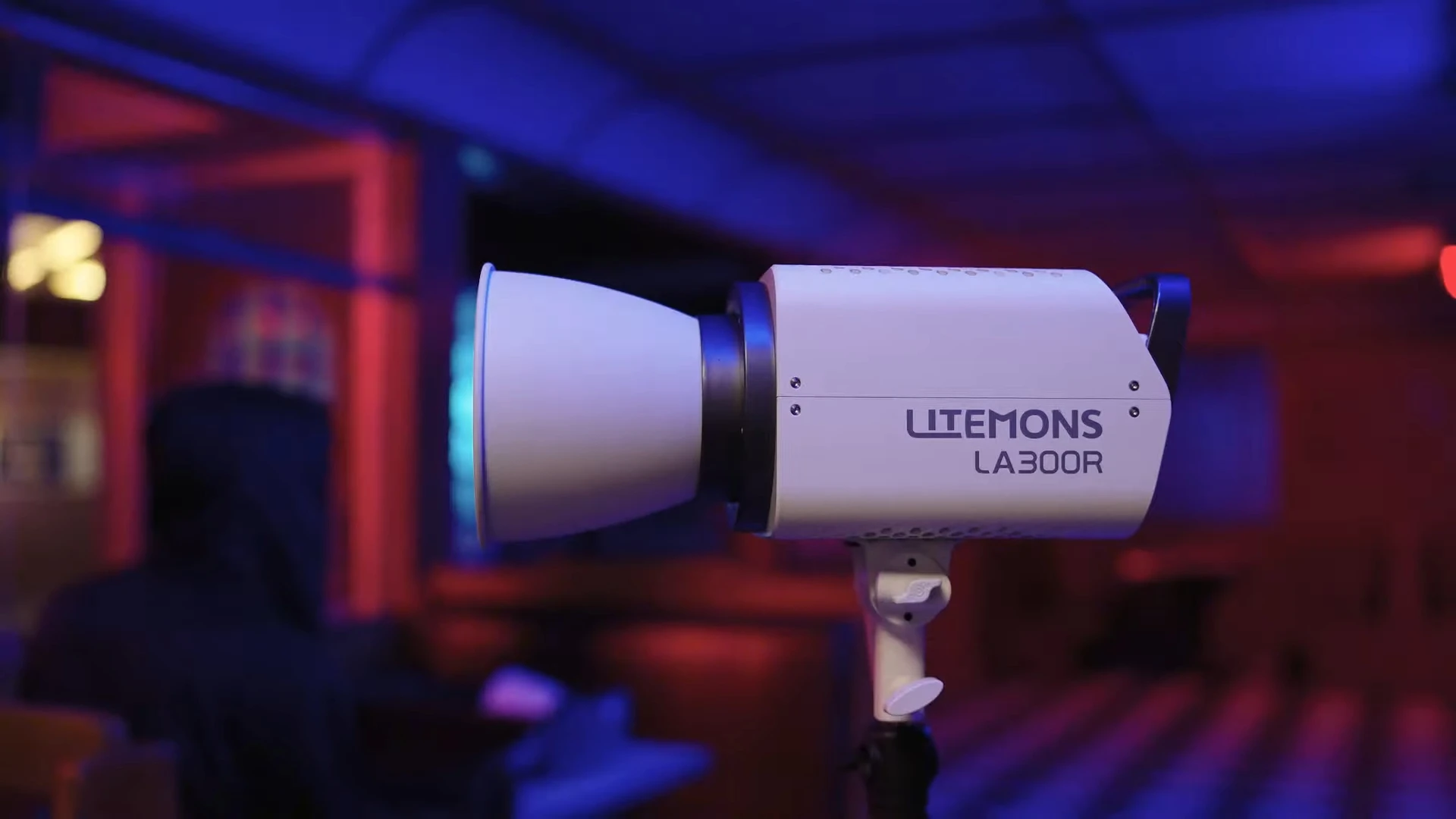 Моноблок Godox Litemons LA300R на стійці з рефлектором працює на темній локації з насиченим синім та червоним підсвічуванням