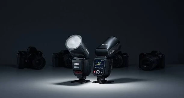 Дві накамерні спалахи Godox V100 на підставках у студії: знімний субспалах SU-1 спереду та кольоровий сенсорний дисплей ззаду