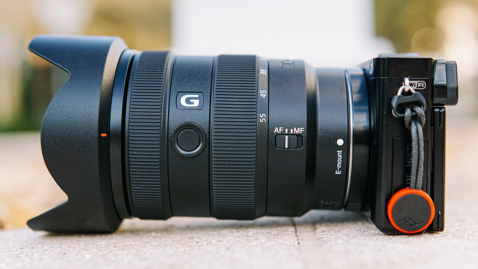 Об'єктив Sony E 16-55mm f/2.8 G з блендою на компактній бездзеркальній камері Sony на світлому кам'яному парапеті