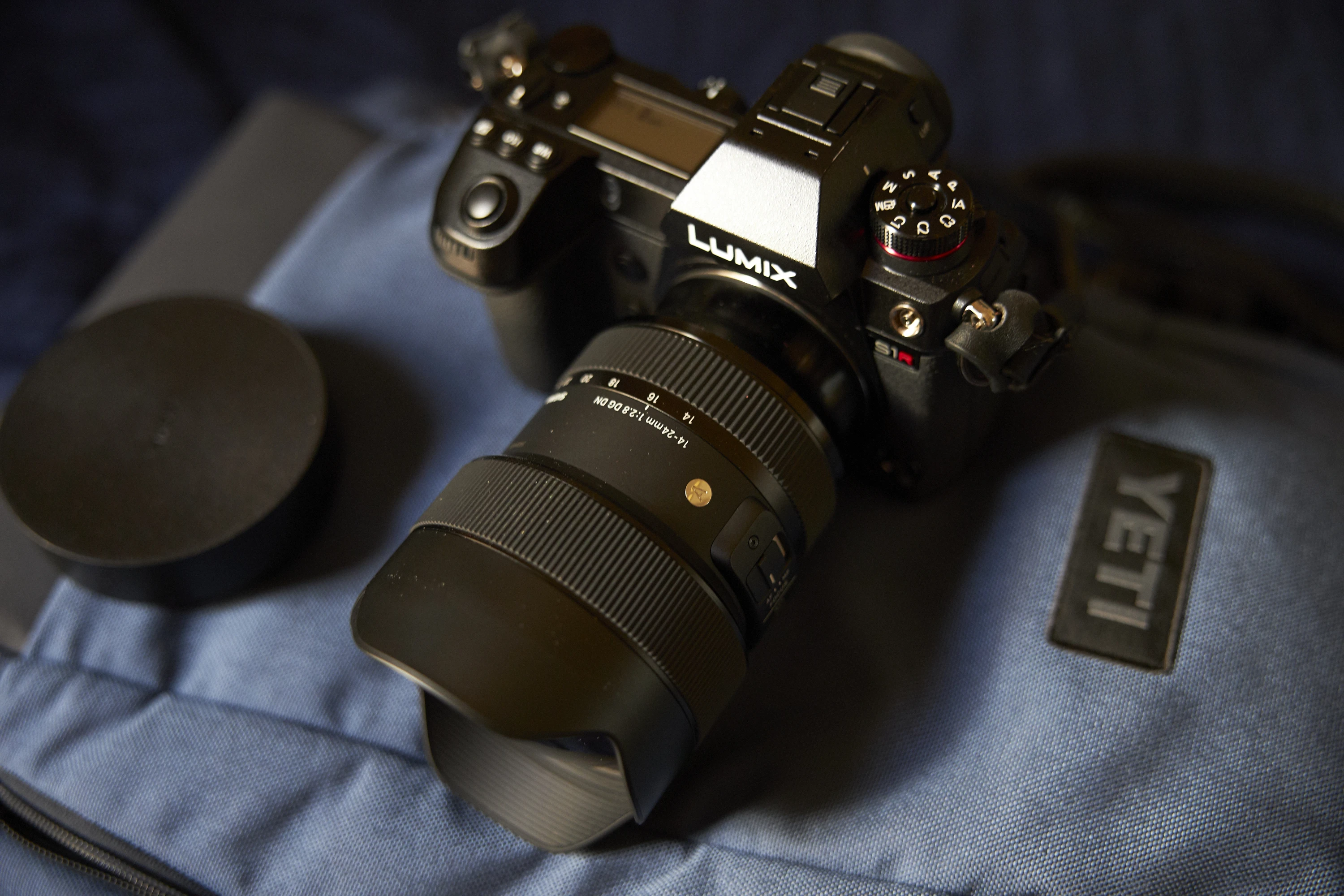 Panasonic Lumix S1R з об'єктивом Sigma 14-24mm f2.8 Art та знятою насувною передньою кришкою поруч