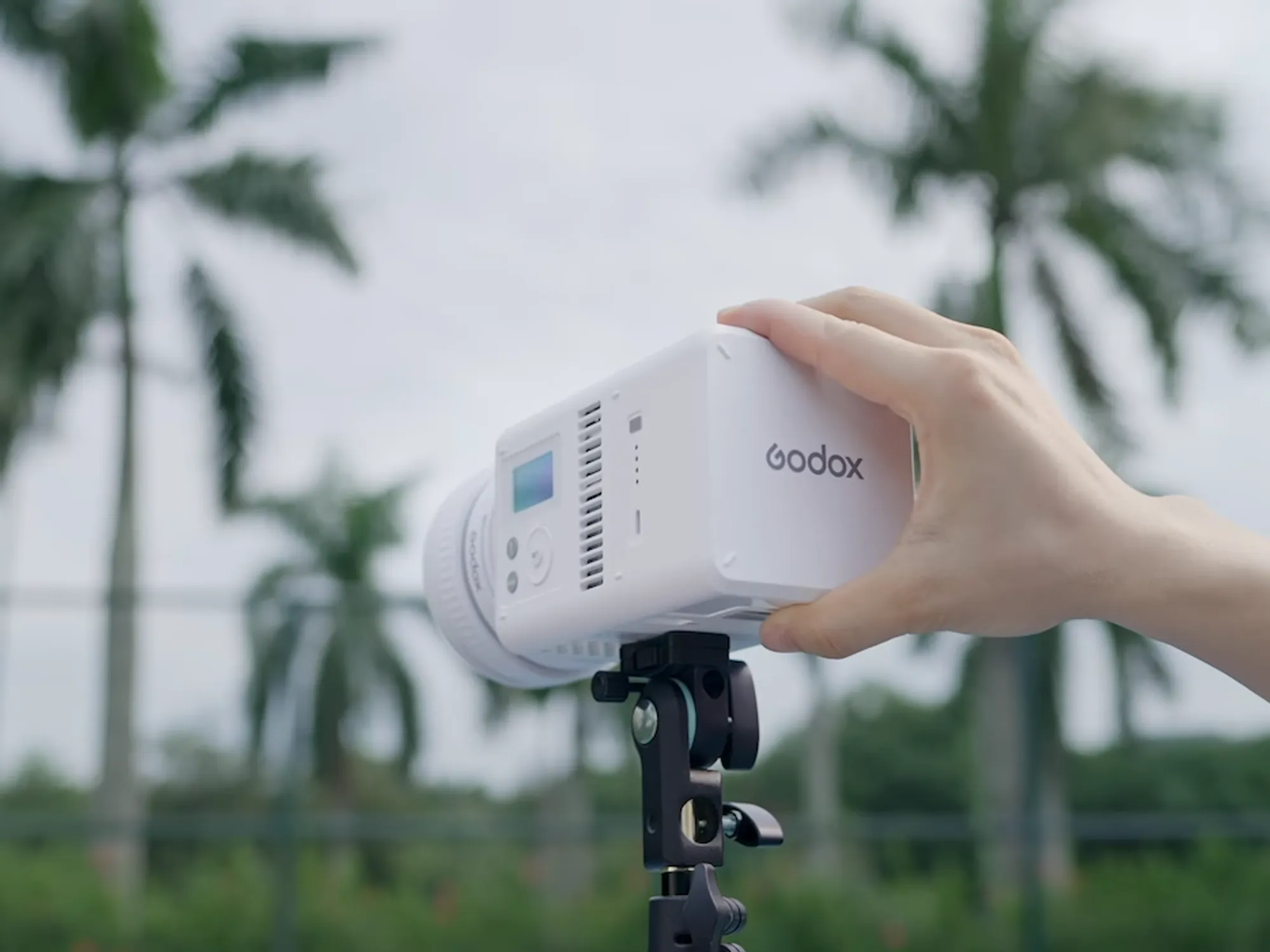 Білий моноблок Godox серії ML закріплений на легкому адаптері штатива під час зйомки на відкритому повітрі