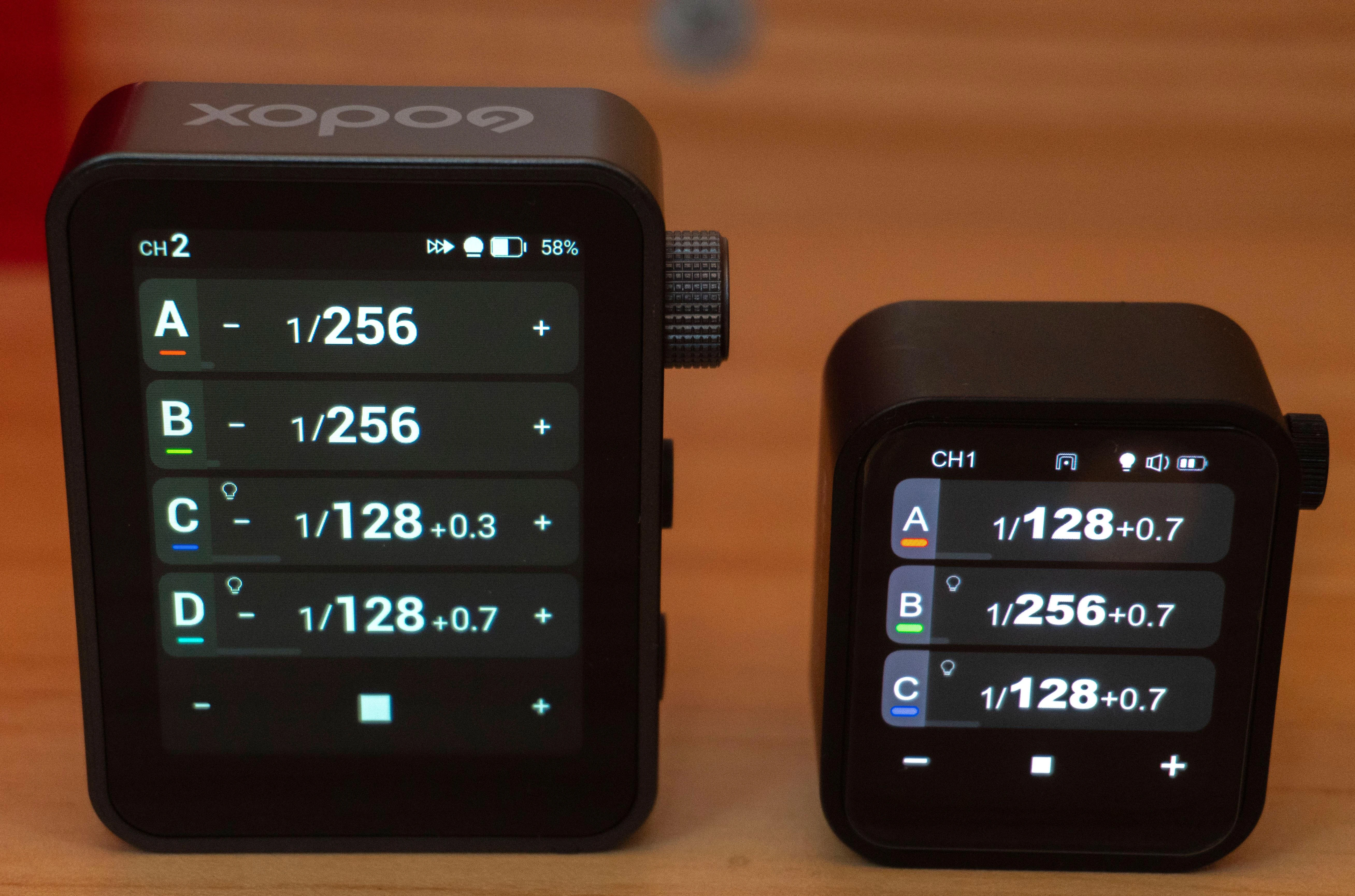 Порівняння розмірів сенсорного синхронізатора Godox X3Pro з екраном 2.4 дюйма та ультракомпактної моделі Godox X3 nano на дерев'яному столі