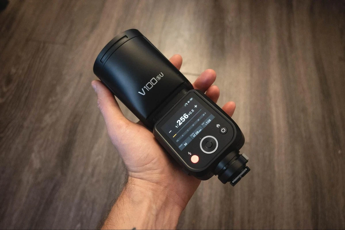 Накамерная вспышка Godox V100 с круглой поворотной головой и магнитным креплением насадок на белом фоне студии