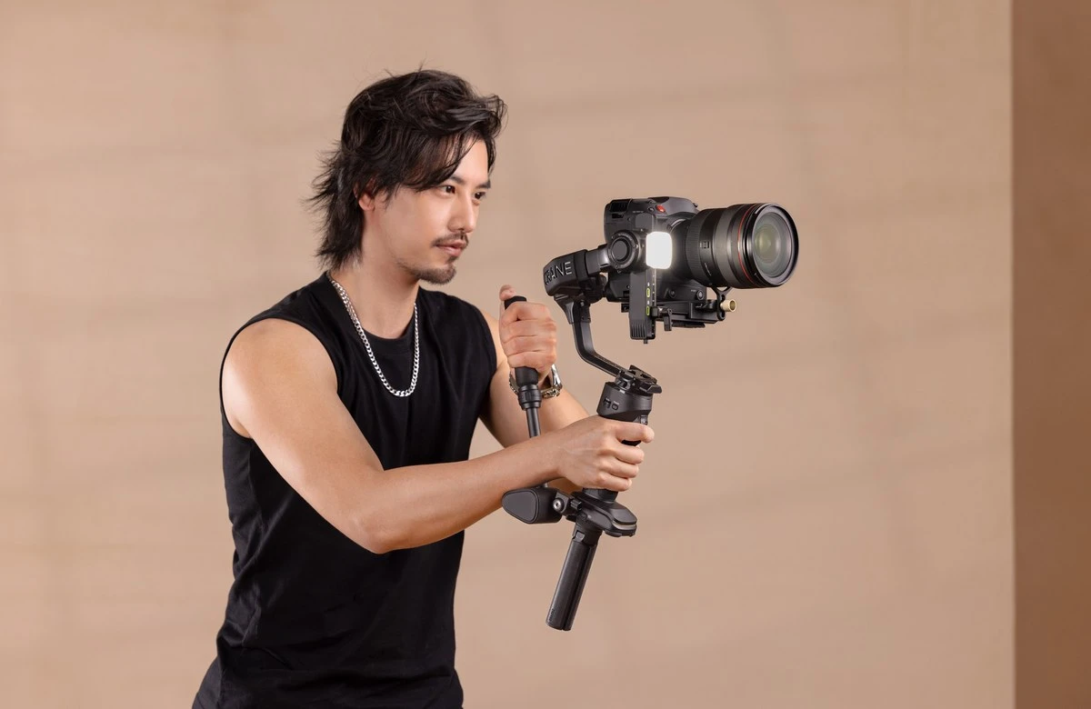 Оператор у студії демонструє дворучний хват стабілізатора Zhiyun Crane 4 з ручкою Sling Handle та упором Wrist Rest