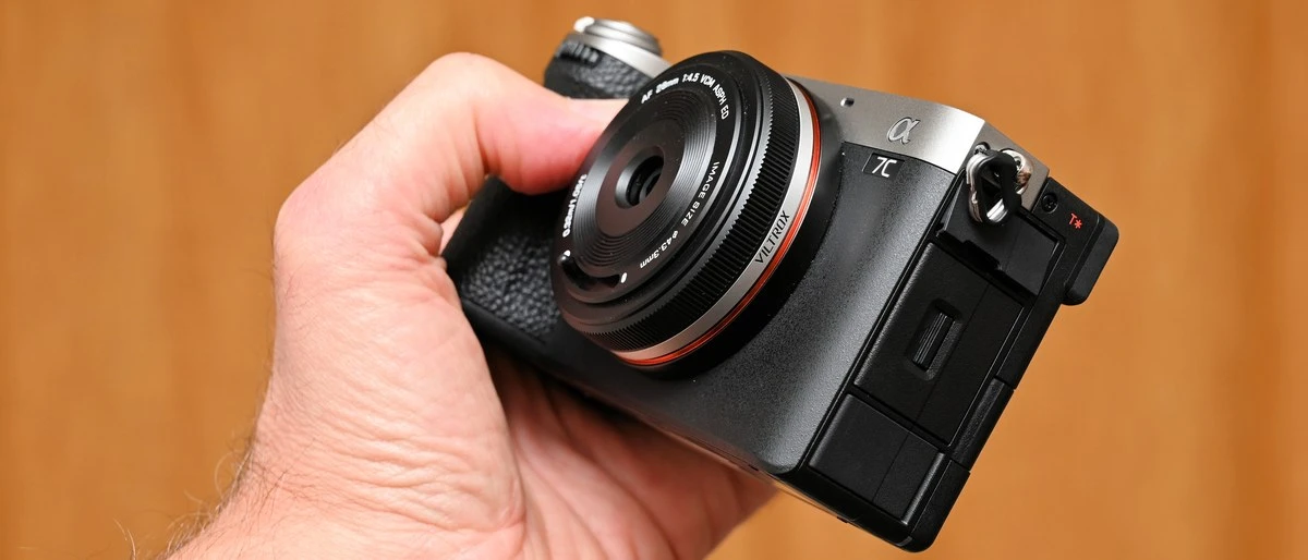 Ультракомпактный объектив Viltrox AF 28mm f/4.5 Chip на полнокадровой беззеркальной камере Sony A7C II, виден рычажок закрытия встроенной шторки.