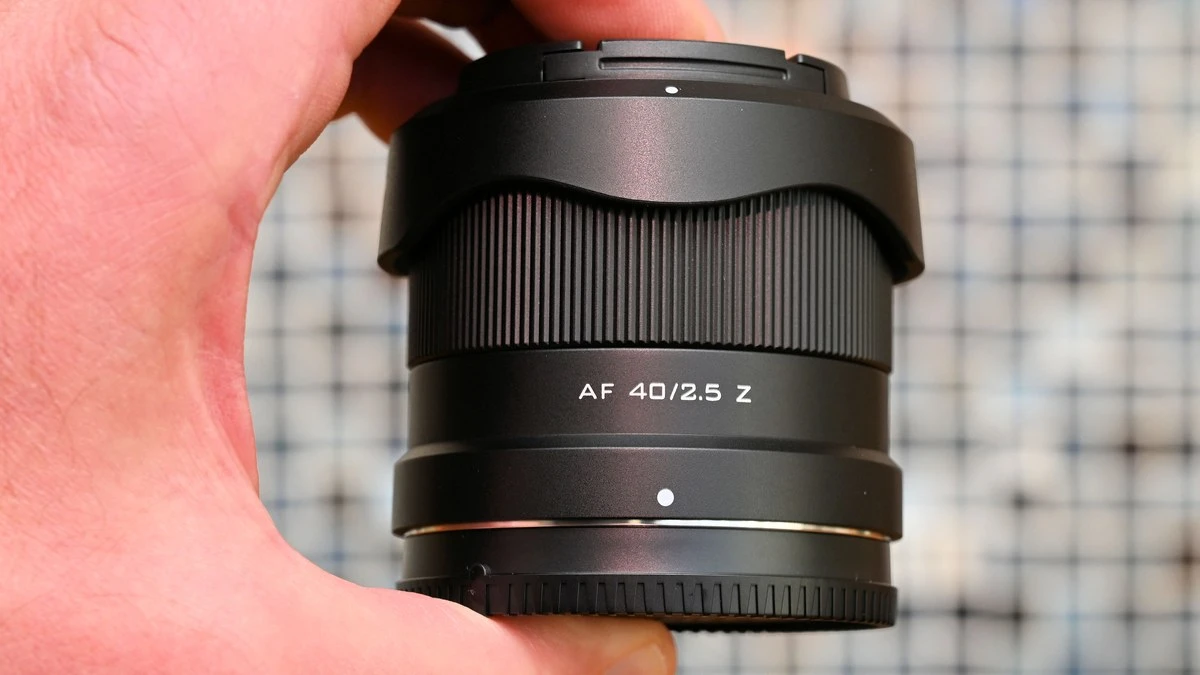Объектив Viltrox AF 40mm f/2.5 Z в руке в компактном транспортировочном положении с перевернутой блендой и задней крышкой байонета.