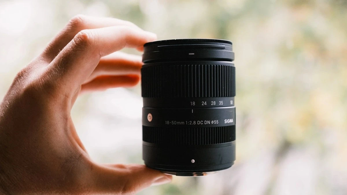Компактный зум-объектив Sigma 18-50mm F2.8 DC DN Contemporary удерживается пальцами одной руки