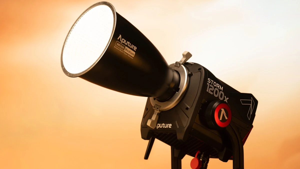 Моноблок Aputure STORM 1200x на П-подібній лірі з рефлектором Hyper Reflector Medium випромінює світло на золотисто-помаранчевому студійному фоні
