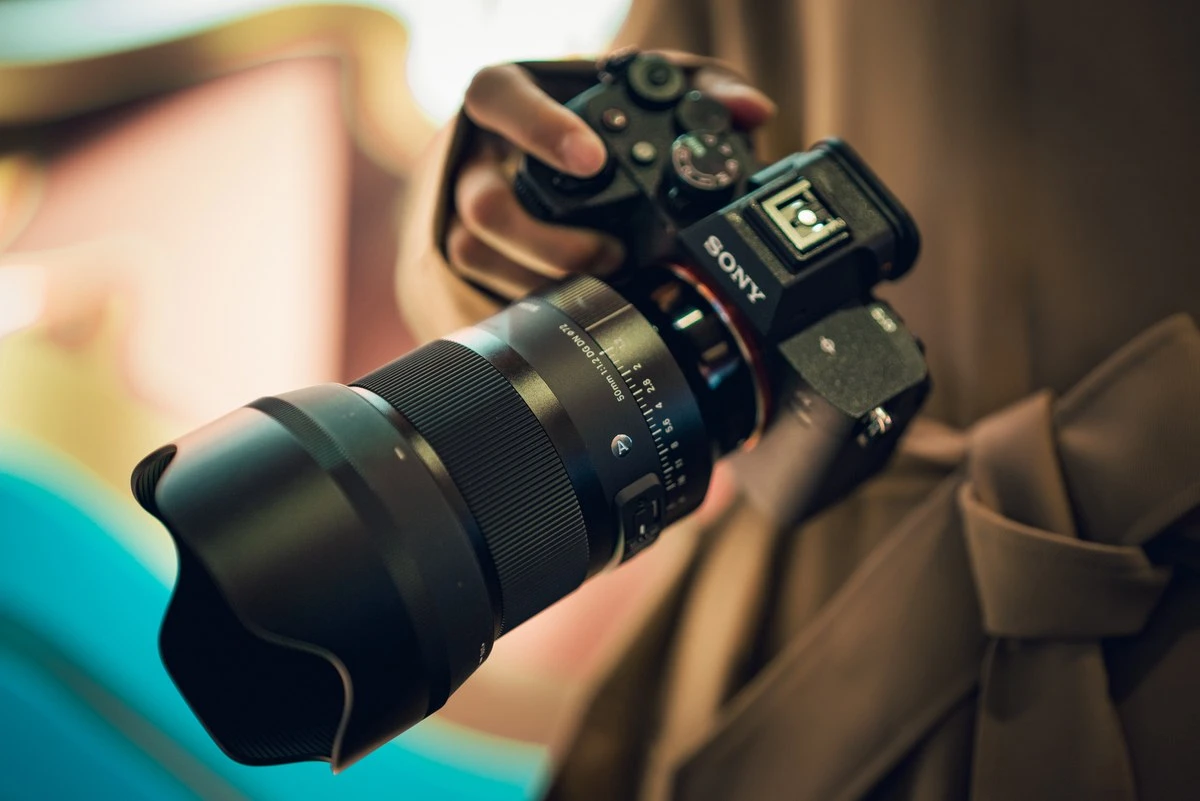 Об'єктив Sigma 50mm f1.2 DG DN Art у руках фотографа на дерев'яній підлозі крупним планом