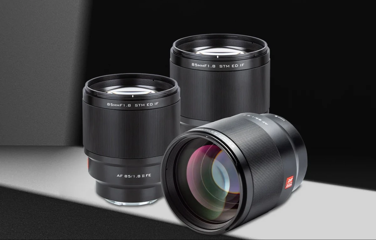Три портретні об'єктиви Viltrox AF 85mm f1.8 II FE на світлому студійному подіумі: два стоять, третій лежить уперед лінзою, видно широке кільце фокусування та маркування внутрішнього фокусування IF