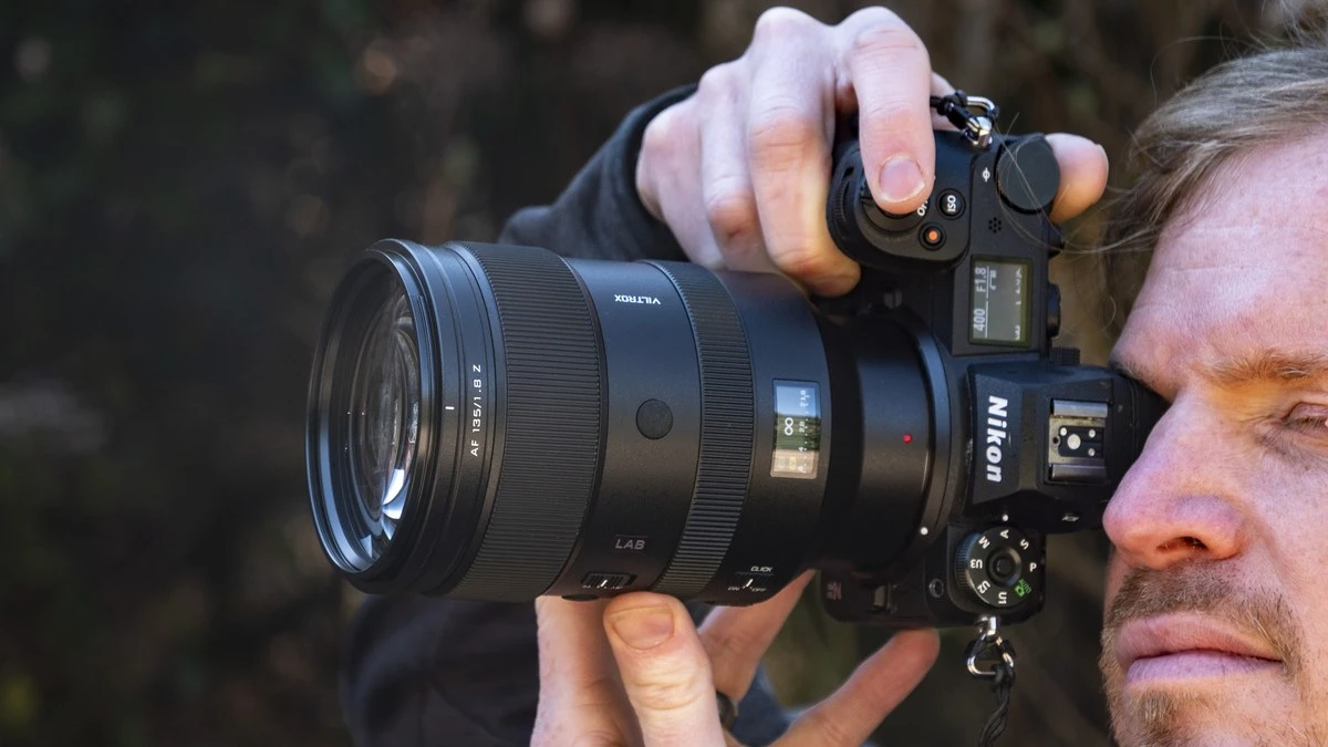 Фотограф утримує двома руками важкий об'єктив Viltrox AF 135mm f/1.8 LAB з активним дисплеєм під час зйомки з рук