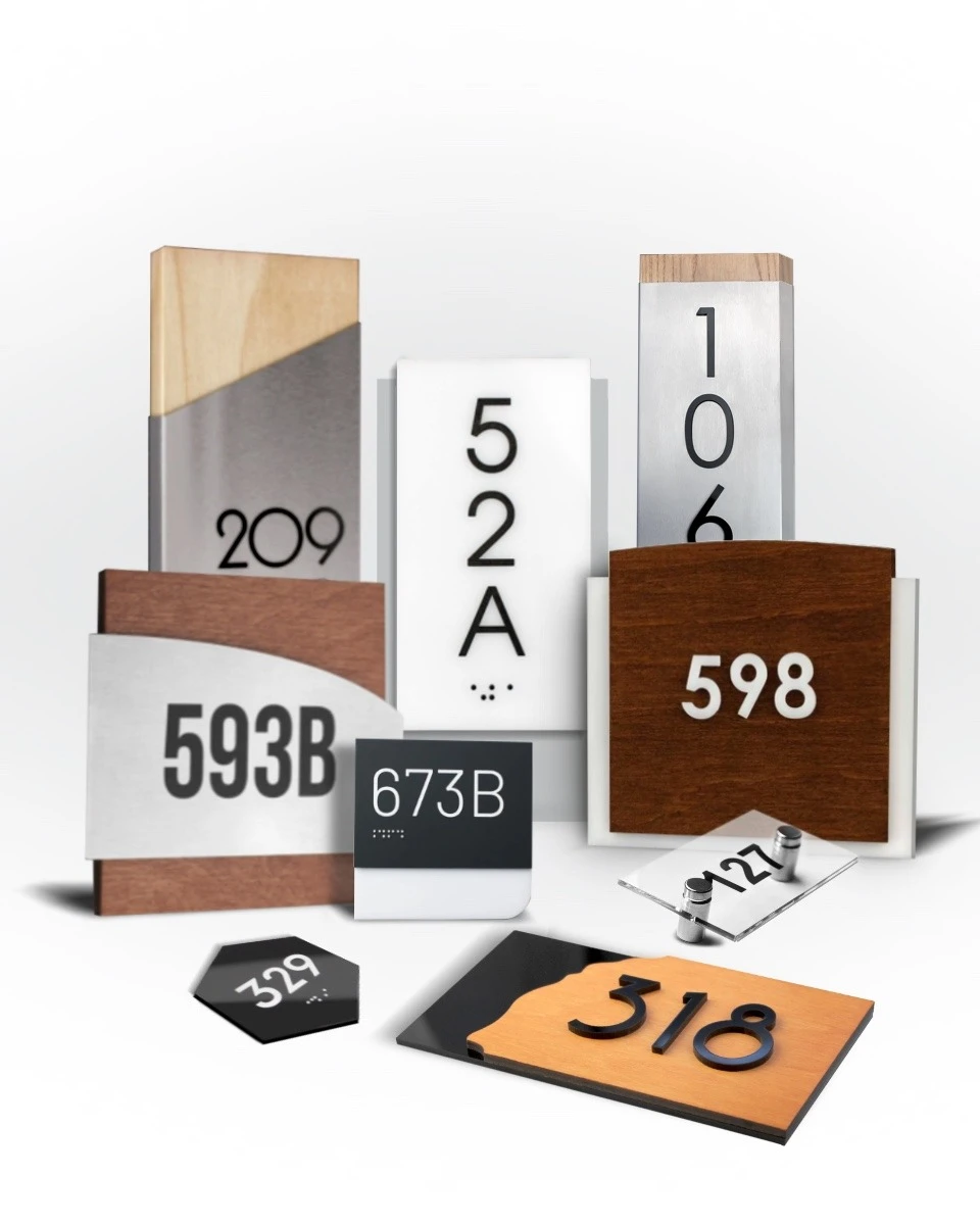 Collection of room number signs in diverse styles — wood, acrylic, brushed metal, and glass with standoff mounts