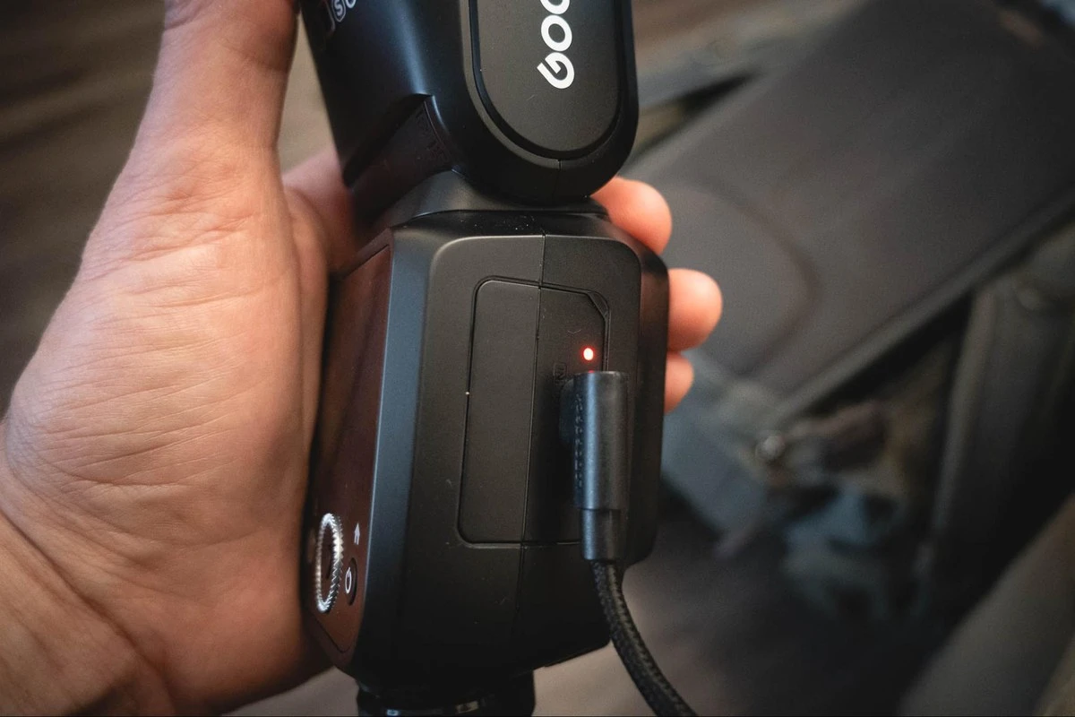 Підключення зарядного кабелю USB-C до акумулятора VB30 у корпусі спалаху Godox V100C з червоним індикатором живлення