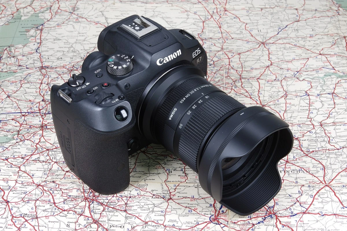 Объектив Sigma 18-50mm f/2.8 DC DN Contemporary с блендой LH582-02 на камере Canon EOS R7, расположенный на развернутой топографической дорожной карте