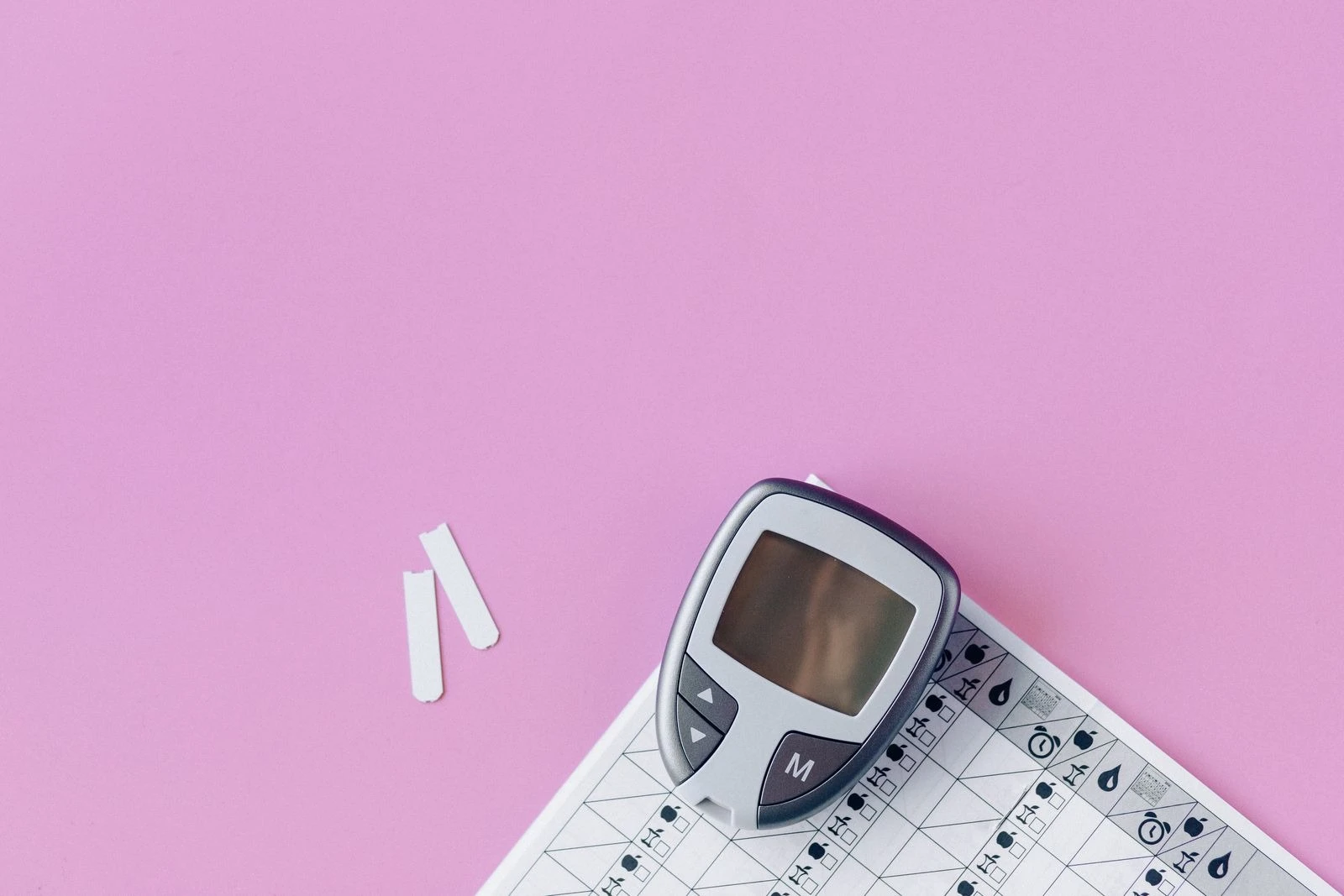 Blood glucose meter and test strips on a pink surface