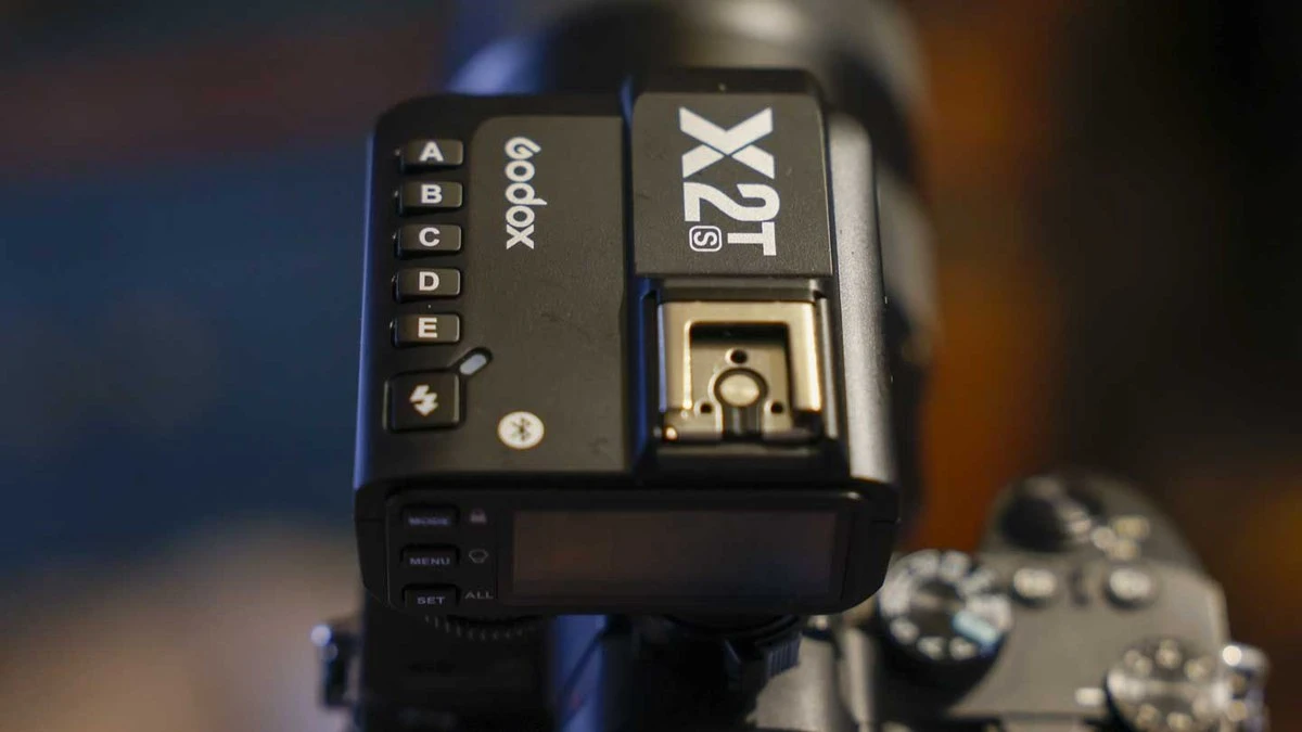 Верхня площина синхронізатора Godox X2T-S на камері з виділеними клавішами груп A-E та металевим наскрізним гарячим башмаком.