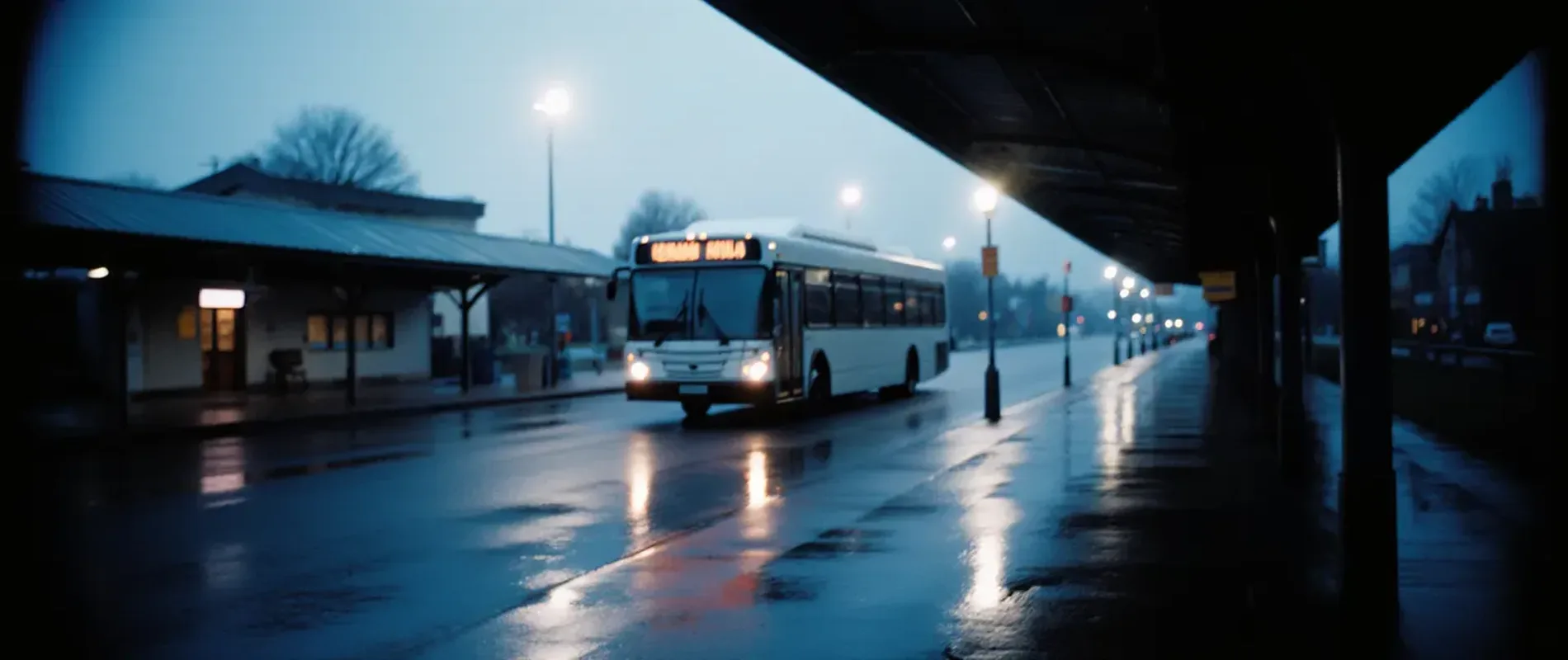 Peron de autogară &icirc;n zori, cu un autobuz interurban care pleacă