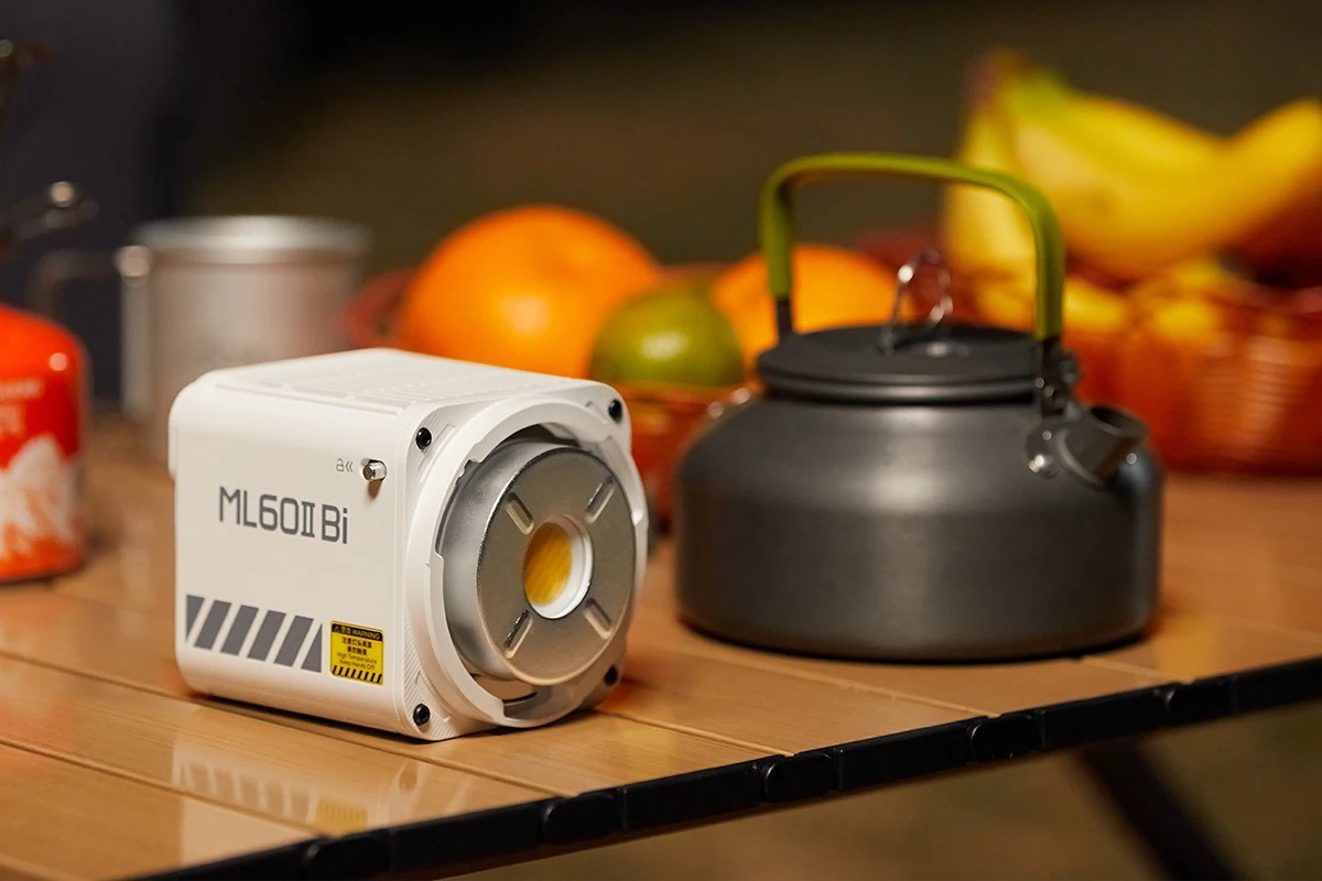 Світлодіодний прилад Godox ML60II Bi з відкритим байонетом Godox Mount поруч із металевим похідним чайником на дерев'яному столі