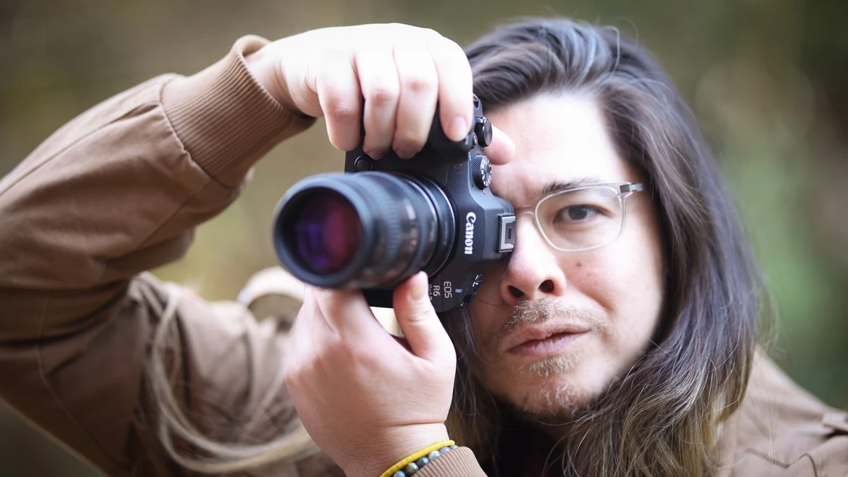 Чоловік у бежевій куртці знімає через видошукач камери Canon EOS R6 Mark III з зум-об'єктивом 24-105mm на відкритому повітрі
