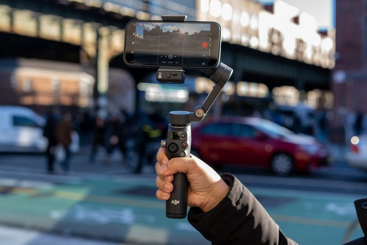 Репортёр идёт по улице со смартфоном на стабилизаторе DJI Osmo Mobile 7P в руке