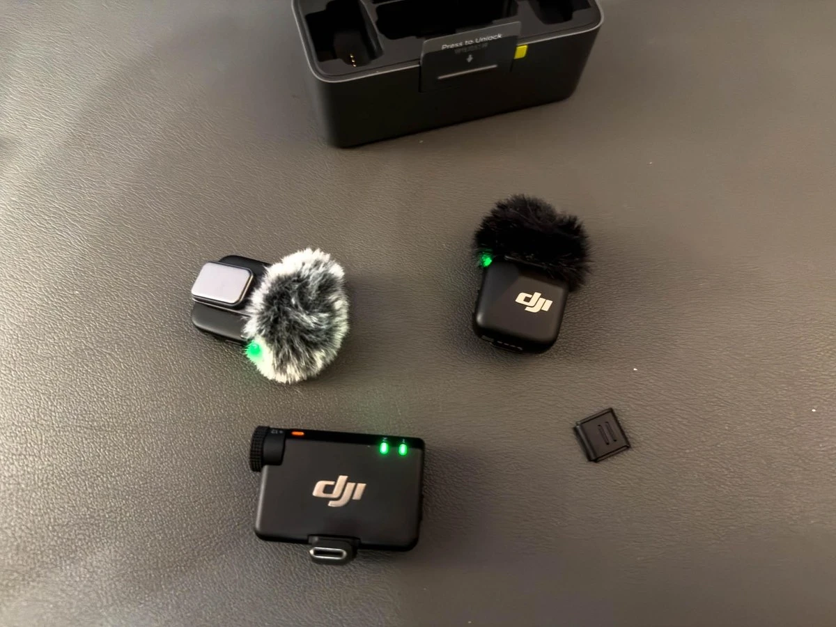 Передатчики DJI Mic Mini с ветрозащитами рядом с приёмником на столе